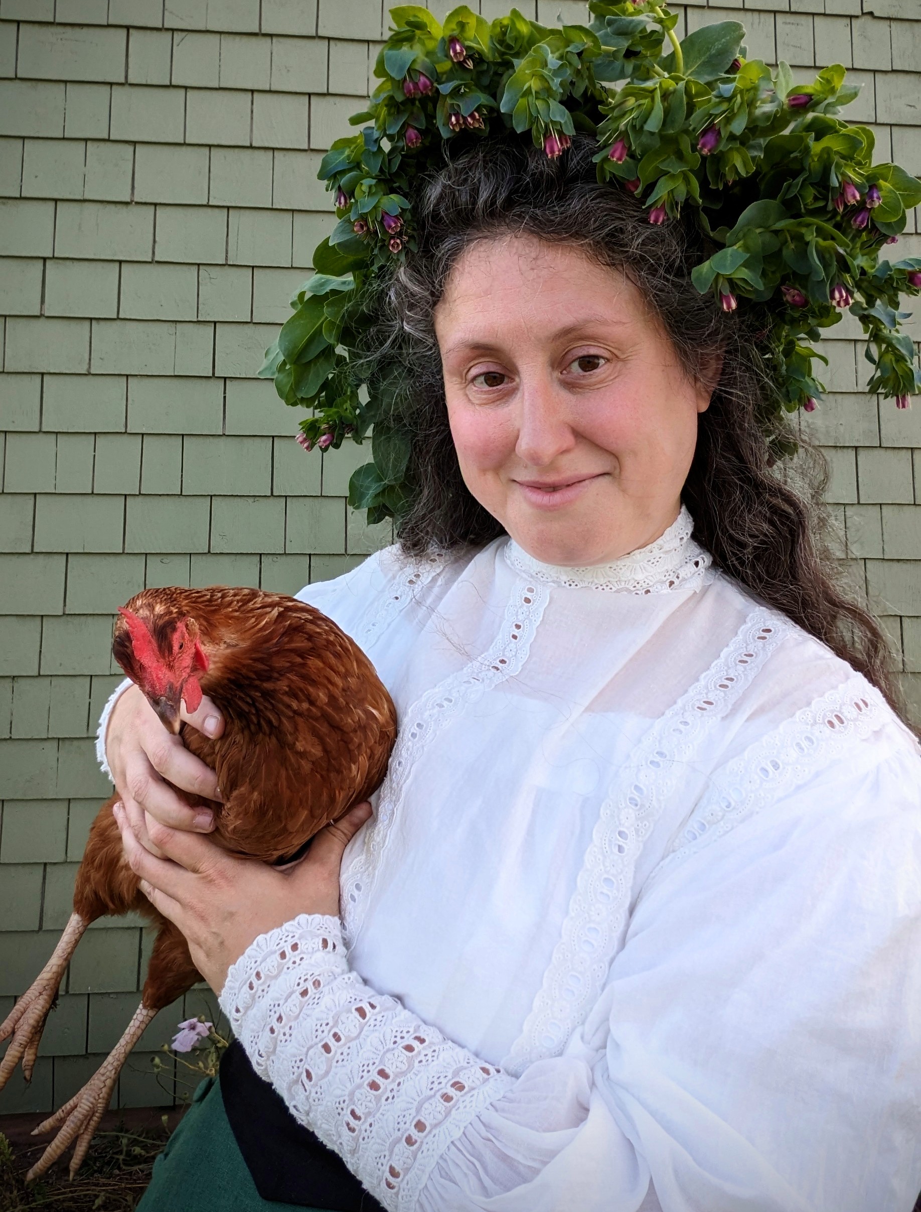 Caitlyn in honeywort crown holding a chicken.