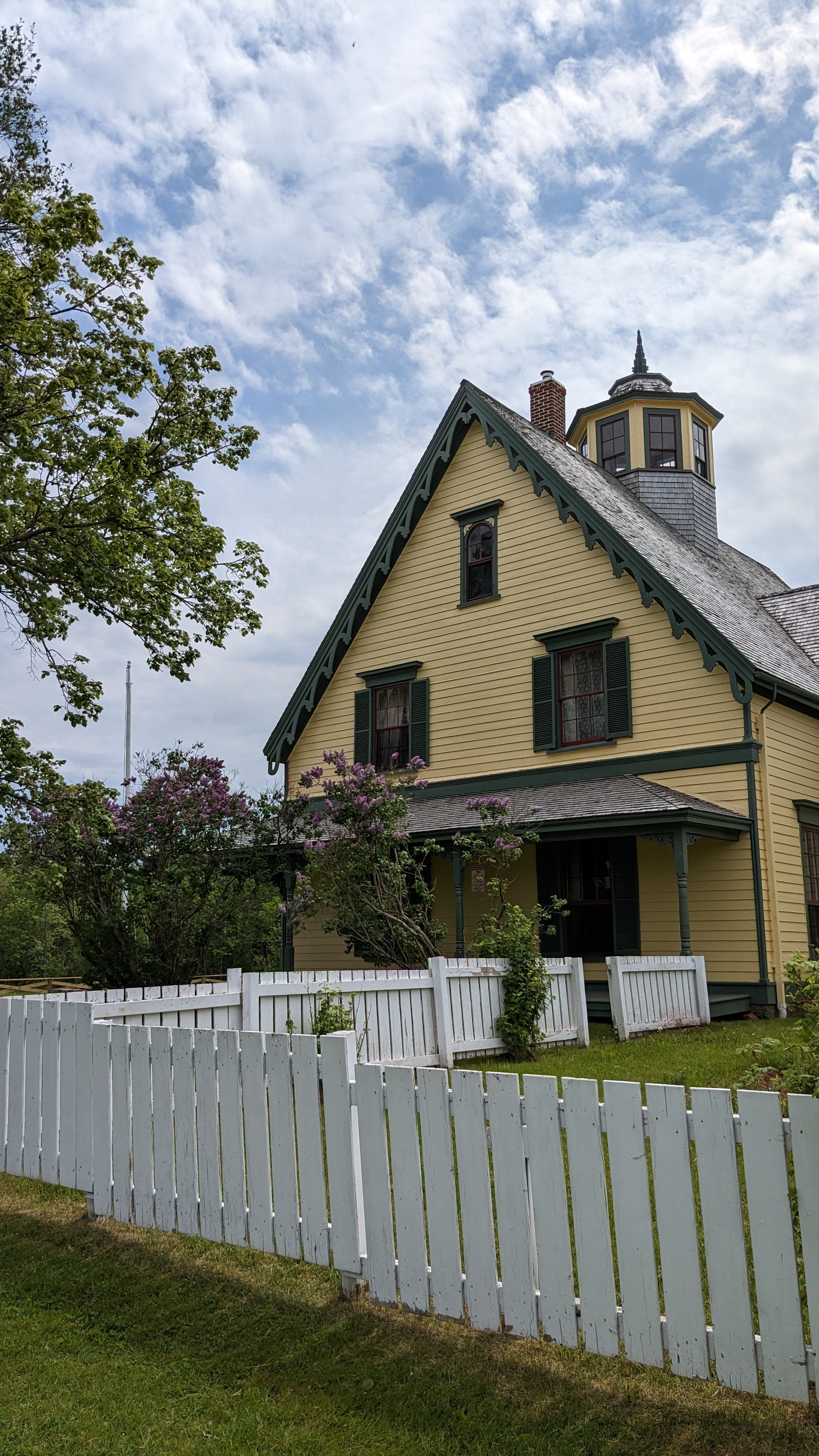 A yellow historic house with green trim. 