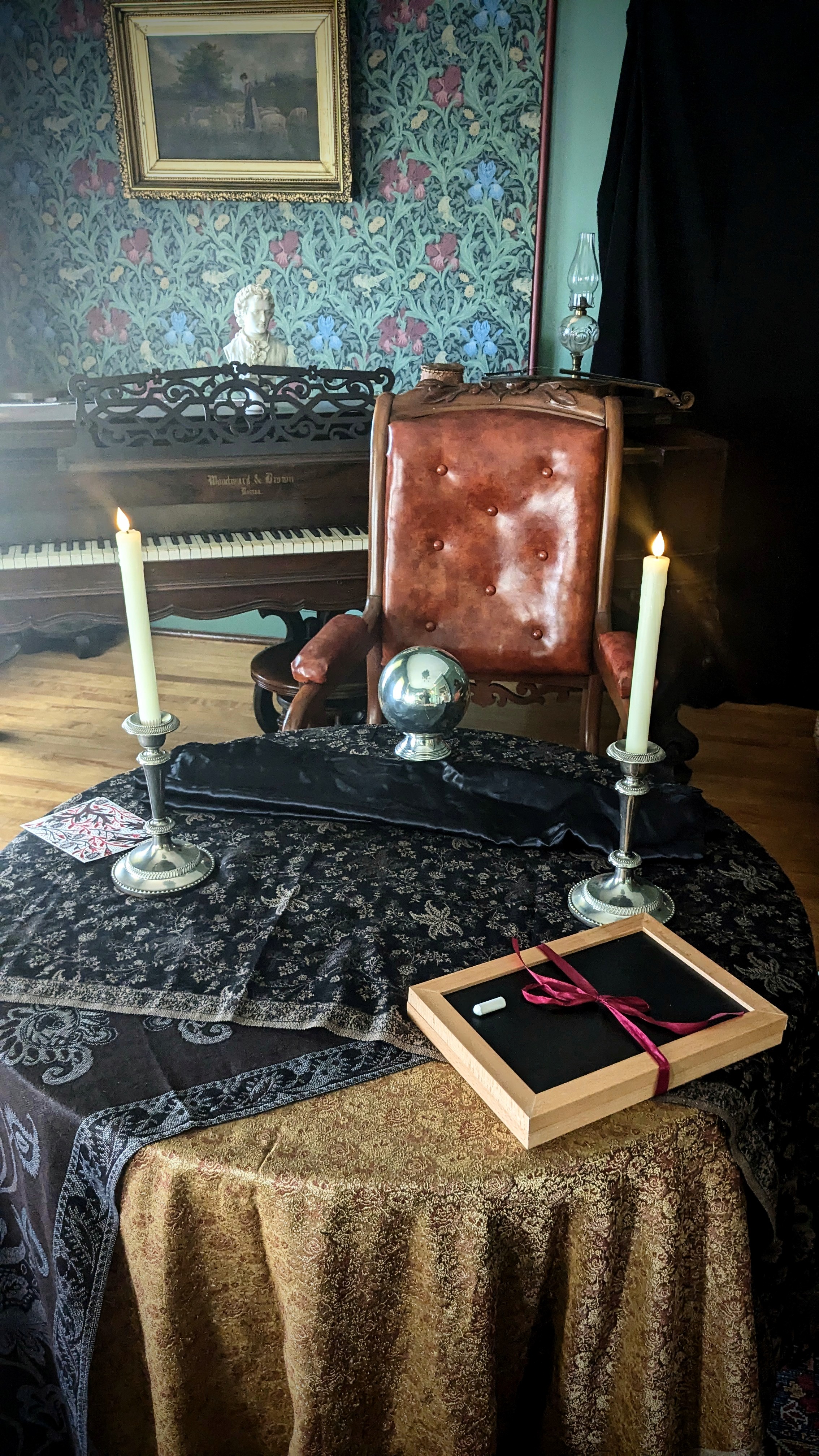 A table with a silver orb and slate on it in a Victorian drawing room.