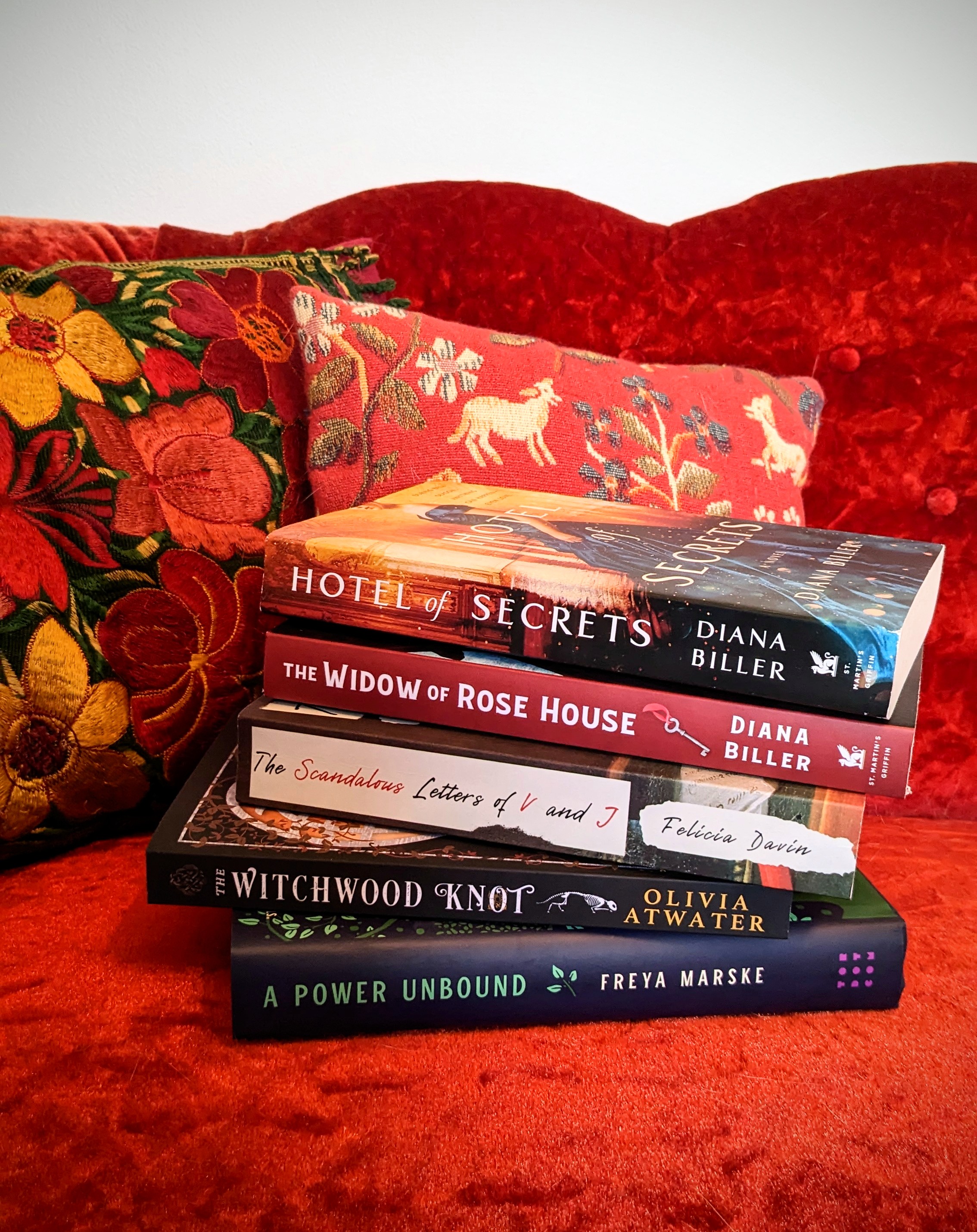 A stack of books on a red chaise.